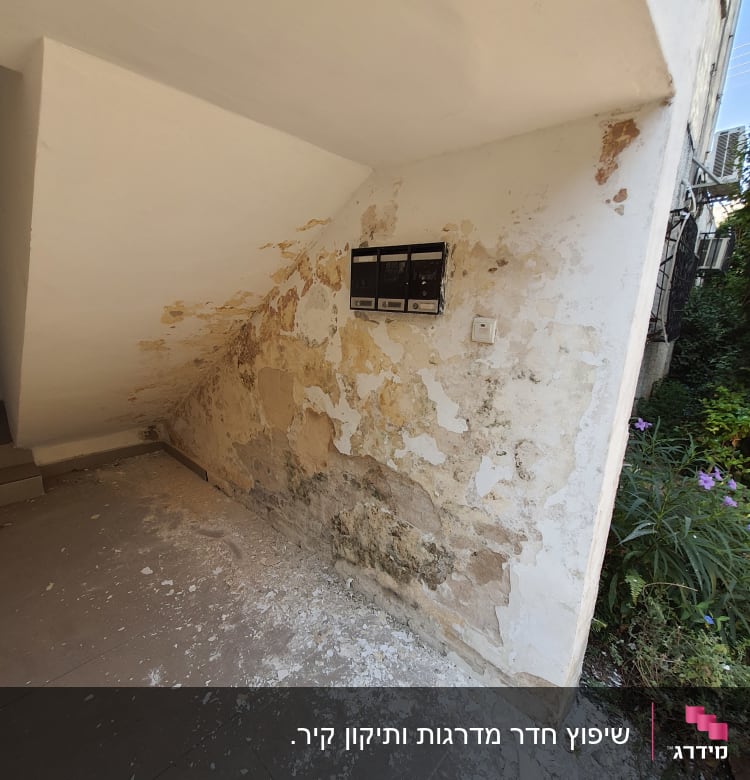 קיר מתקלף עם טיח מתפורר ופסולת על הרצפה